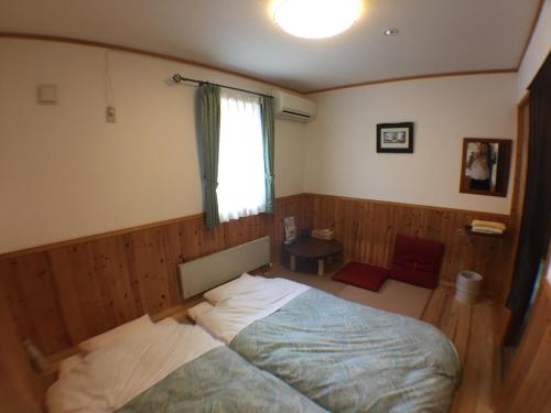 a bedroom with a bed and a window at Pension Jokura in Hakodate