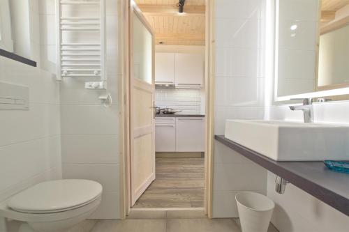 een witte badkamer met een toilet en een wastafel bij Dębki DeLuxe in Dębki