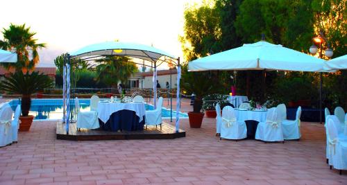 een groep tafels en parasols naast een zwembad bij Agriturismo Arabesque in Balestrate