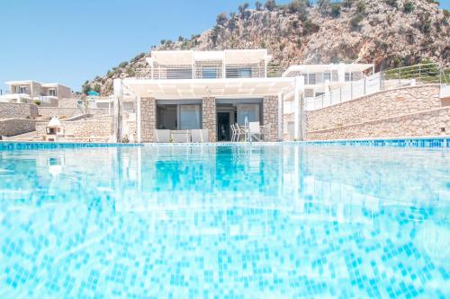 a swimming pool with blue water in front of a house at Francis & Gregorys Luxury Villas in Afantou