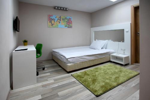 a bedroom with a white bed and a green rug at Executive Rooms and Suites Play in Veliko Tŭrnovo