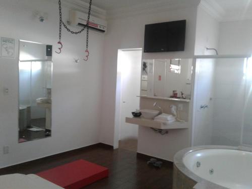 a white bathroom with a sink and a tub at Prime Motel in Criciúma