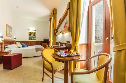 a hotel room with a table and chairs and a bed at Hotel Duomo in Orvieto