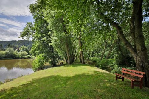 a park bench sitting on the grass next to a lake at Romantic Hotel Mlýn Karlstejn in Karlštejn