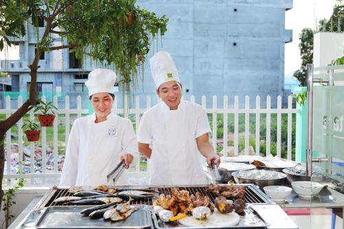 two chefs standing in front of a grill with food at Gold Stars Hotel in Long Hai