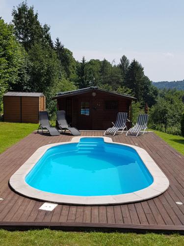 a swimming pool on a deck with chairs and a cabin at BLUE PENSION s bazénem in Svoboda nad Úpou