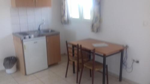 a kitchen with a table and chairs and a sink at Studios Kapsalas in Néa Michanióna