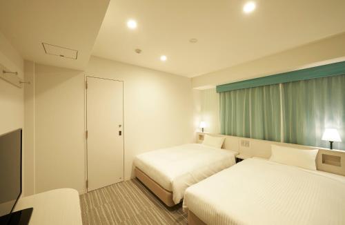 a hotel room with two beds and a television at Sotetsu Fresa Inn Ginza Sanchome in Tokyo