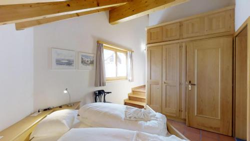 a room with two beds and a wooden cabinet at Prüveda A2.1 in Silvaplana