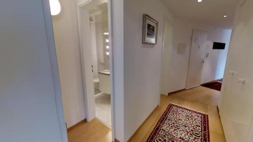 a hallway with a bathroom with a toilet and a rug at Paravicini in St. Moritz