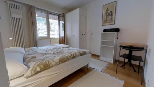 ein Schlafzimmer mit einem Bett und einem Tisch und einem Fenster in der Unterkunft Paravicini in St. Moritz