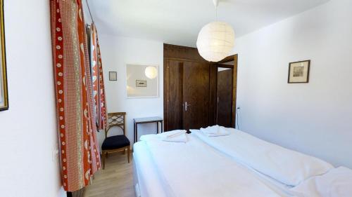a bedroom with a white bed and a chair at Collina in Celerina