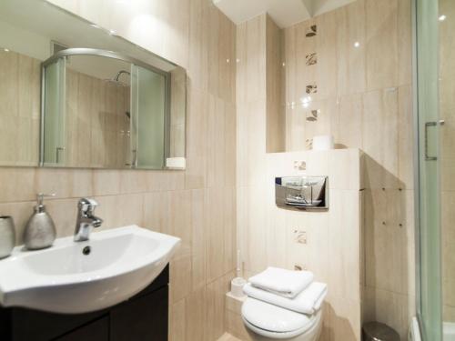 W łazience znajduje się umywalka, toaleta i lustro. w obiekcie Pałacowa Condominium w mieście Białystok