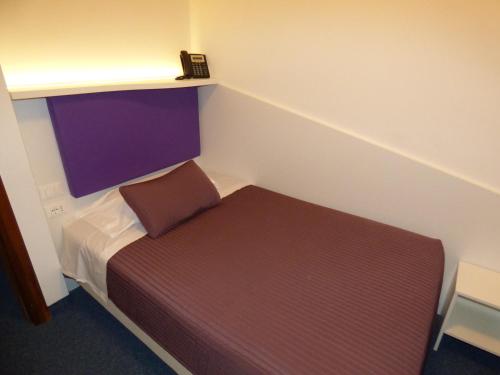 a small room with a bed and a phone on a shelf at Mon Repos in Lido di Jesolo