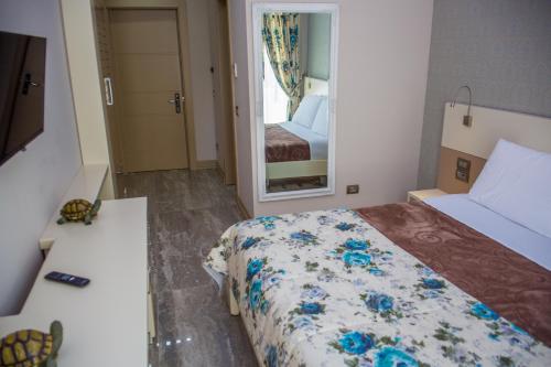 a small bedroom with a bed and a mirror at Hotel Vila Koral in Durrës