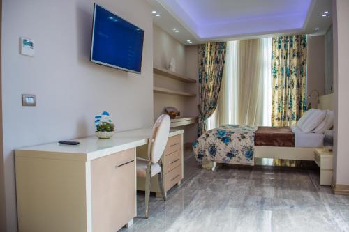a hotel room with a desk and a bed and a television at Hotel Vila Koral in Durrës
