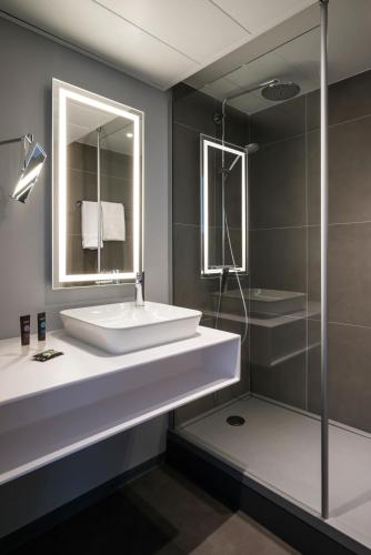 a bathroom with a white sink and a shower at Novotel Saclay in Saclay