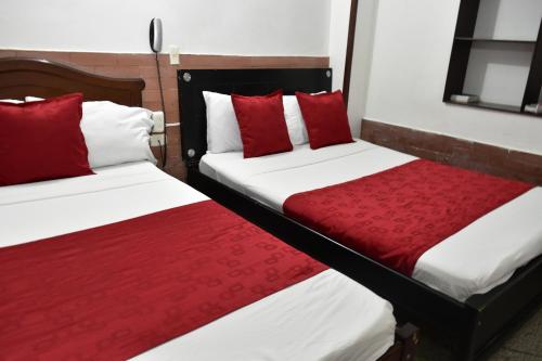 Duas camas com almofadas vermelhas num quarto em Hotel El Principe em Ocaña