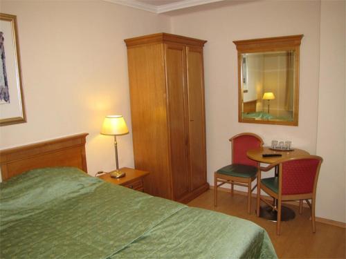 a bedroom with a bed and a table and a chair at Pávai Vendégház in Hajdúszoboszló