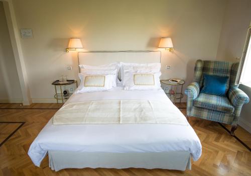 a bedroom with a large white bed and a blue chair at Castello Di Mornico Losana in Mornico Losana