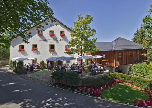 un bâtiment avec des tables et des parasols devant lui dans l'établissement Klostergasthof Maria Eck, à Siegsdorf