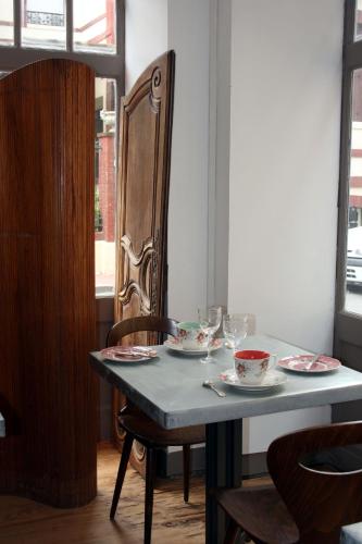 a table with plates and wine glasses on it at La Maison de la Plage in Trouville-sur-Mer