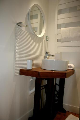 a bathroom with a sink and a mirror on a table at La Maison de la Plage in Trouville-sur-Mer