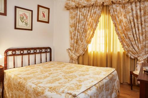 a bedroom with a bed and a window with curtains at Casa D Obidos in Óbidos
