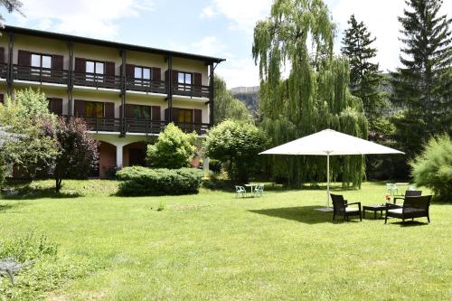 a building with a table and an umbrella in the yard at Hôtel Lacour in Eygliers