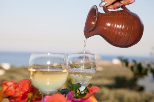 a person pouring white wine into a wine glass at Liviko View in Xerokampos