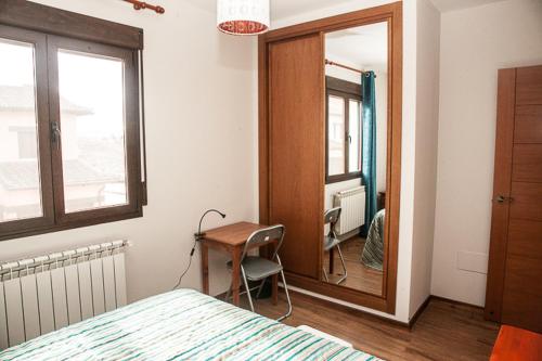 a bedroom with a bed and a desk and a mirror at Apartamento el Palomar in Ayllón