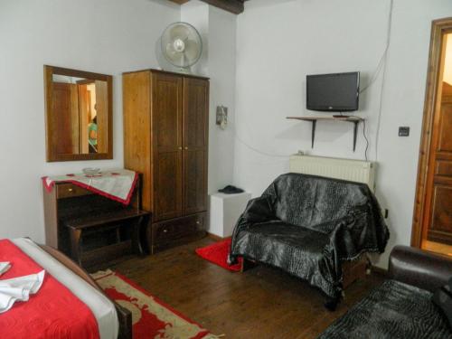 a bedroom with a bed and a chair and a television at Guesthouse Klearchos in Palaios Panteleimon
