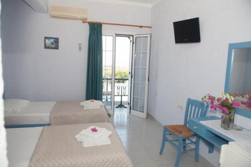 a hotel room with two beds and a desk and a balcony at Liviko View in Xerokampos