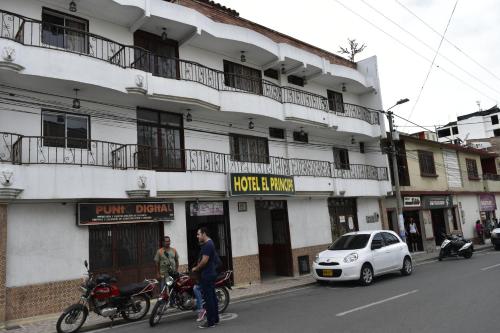 um homem parado ao lado de uma moto em frente a um edifício em Hotel El Principe em Ocaña