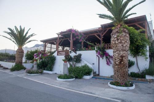 a building with palm trees and flowers in front of it at Liviko View in Xerokampos
