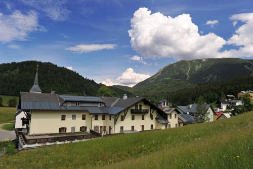 a building on a hill with mountains in the background at Gasthof Kirchenwirt in Lackenhof