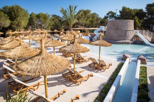 a group of straw umbrellas and chairs next to a swimming pool at Insotel Club Maryland in Playa Migjorn