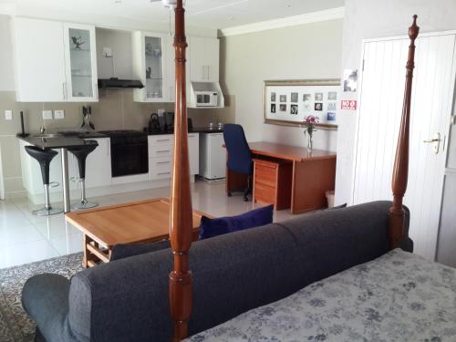 a living room with a couch and a table and a kitchen at Thatchfoord Lodge in Johannesburg