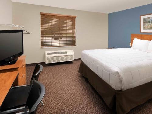 a bedroom with a bed and a flat screen tv at WoodSpring Suites San Antonio North Live Oak I-35 in San Antonio