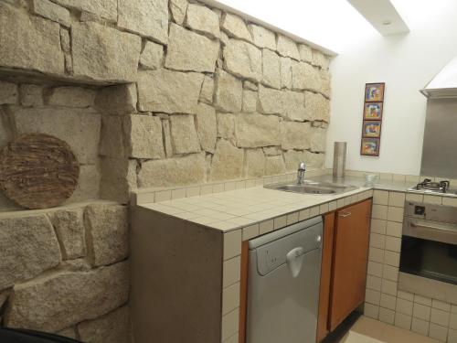 a kitchen with a sink and a stone wall at Casa do O - Alojamento Local in Tábua