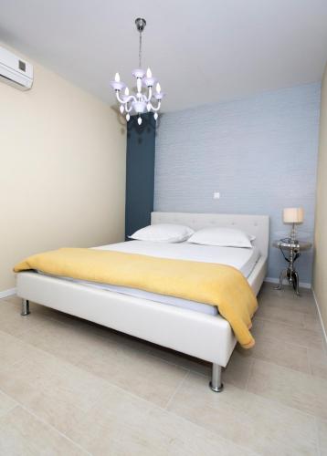 a bedroom with a large white bed with a chandelier at Villa Bougenvilia Tomas in Tučepi