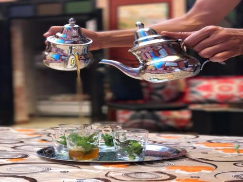 una persona serve un bollitore per il tè su un tavolo di Kasbah Red Castel Hostel a Marrakech