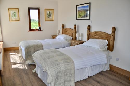 クリフデンにあるIsland View Townhousesの白い壁とウッドフロアの客室で、ベッド2台が備わります。