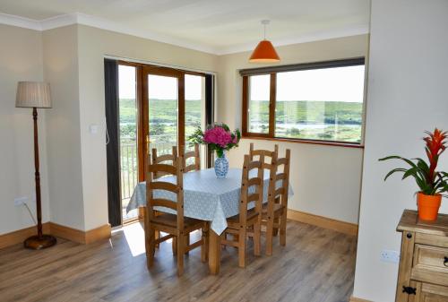 uma sala de jantar com mesa, cadeiras e janelas em Island View Townhouses em Clifden