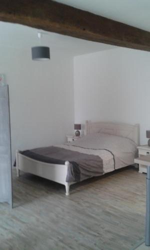 1 dormitorio con 1 cama grande en una pared blanca en Gîte Blonimael, en Vendrennes