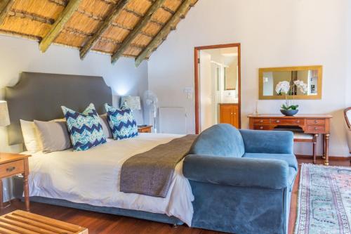 a bedroom with a large bed and a blue chair at Thatchfoord Lodge in Johannesburg