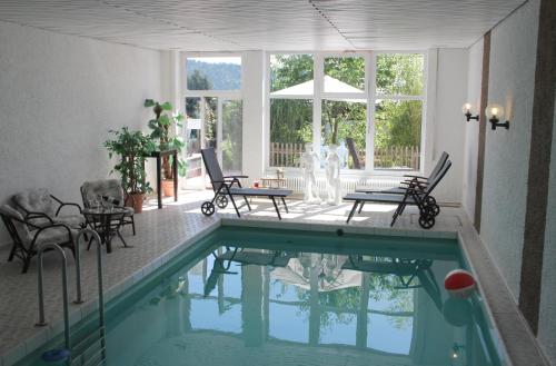 ein Haus mit einem Pool mit Stühlen und einem Tisch in der Unterkunft Villa Relax - Ferienwohnungen & Hallenbad & Relaxgarten in Bodenmais