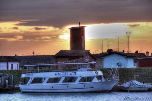 a boat sitting in the water with the sunset in the background at Albergo Ristorante Uspa in Gorino Ferrarese