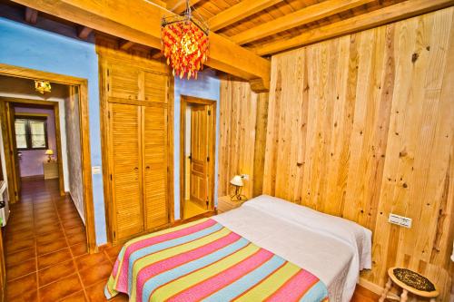 Un dormitorio con una cama en una habitación con paredes de madera. en Casa del Herrero, en Mogarraz