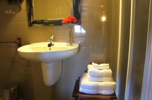 a bathroom with a sink and a pile of towels at Casa Rural Estrela in San Martín de Trevejo